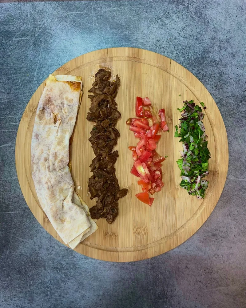 Deconstructed tantuni ingredients on a round wooden board at 33 Tantuni & Doner