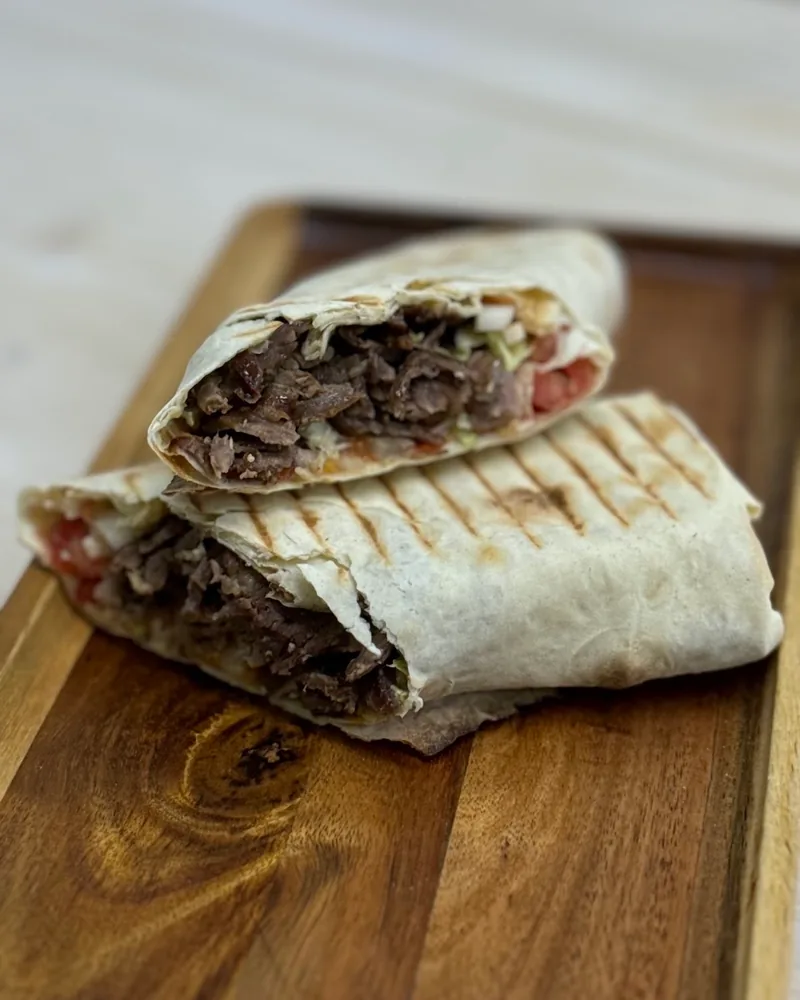 Beef doner wrap halved on a wooden board at 33 Tantuni & Doner