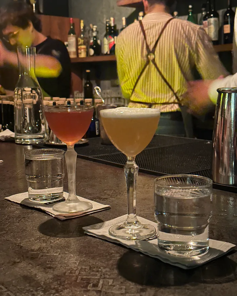Two cocktails in stemmed glasses at the bar at 41° Art of Drinks
