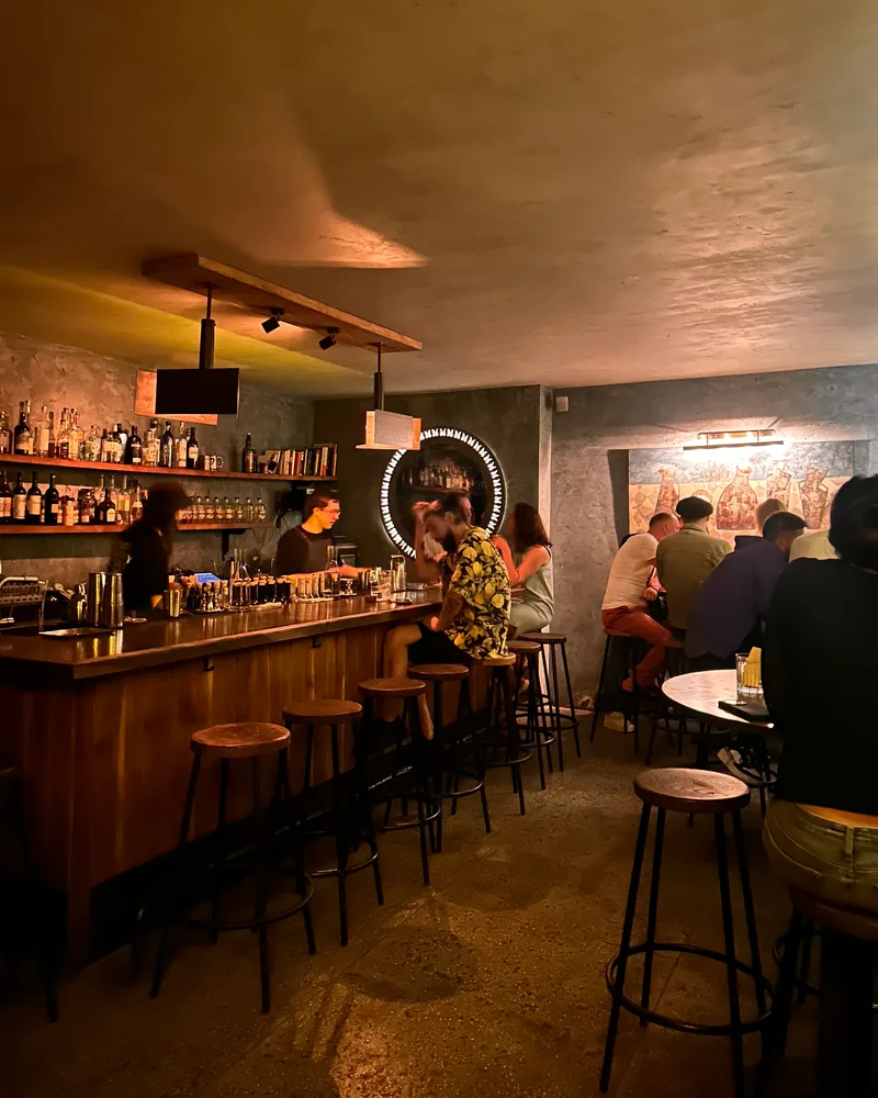 Cocktail bar counter with stools and patrons at 41° Art of Drinks