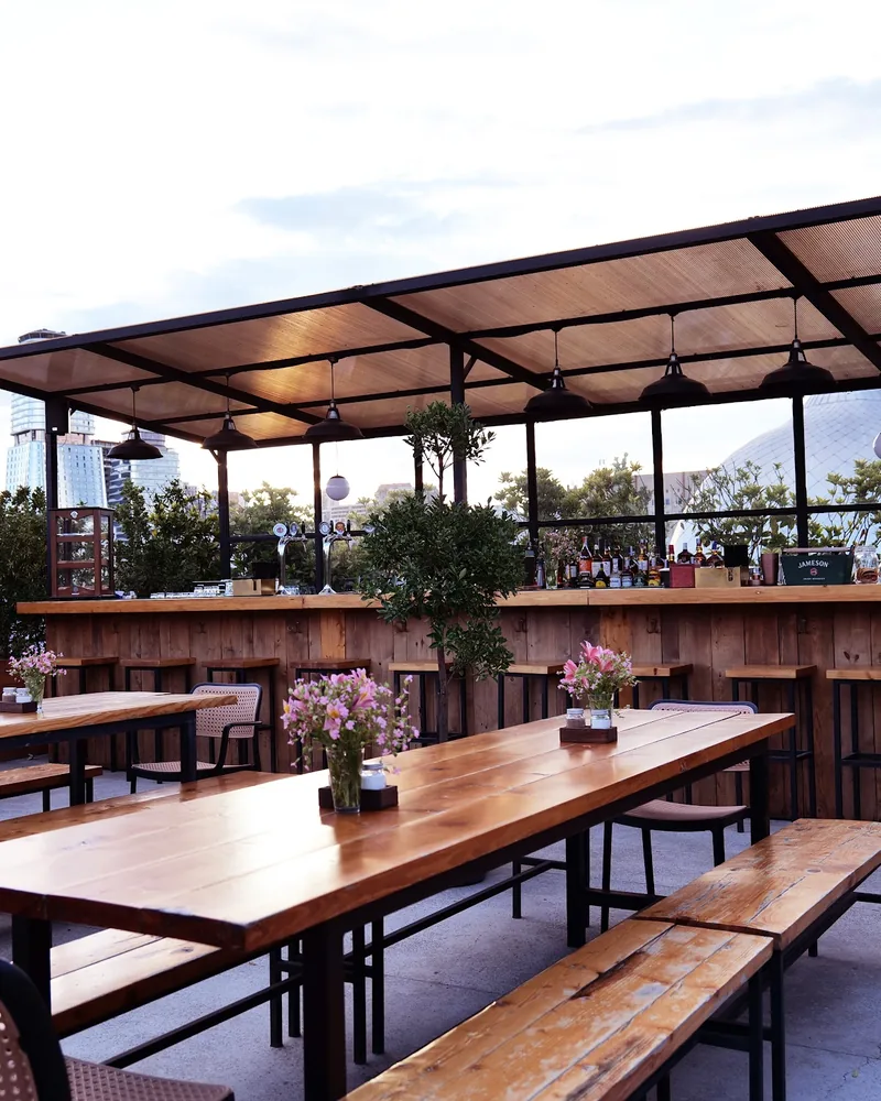 Rooftop terrace with wooden tables and outdoor bar at #8 BBQ House