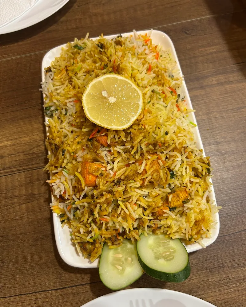 Biryani on a rectangular plate topped with lemon and cucumber slices at Al Madina Cave