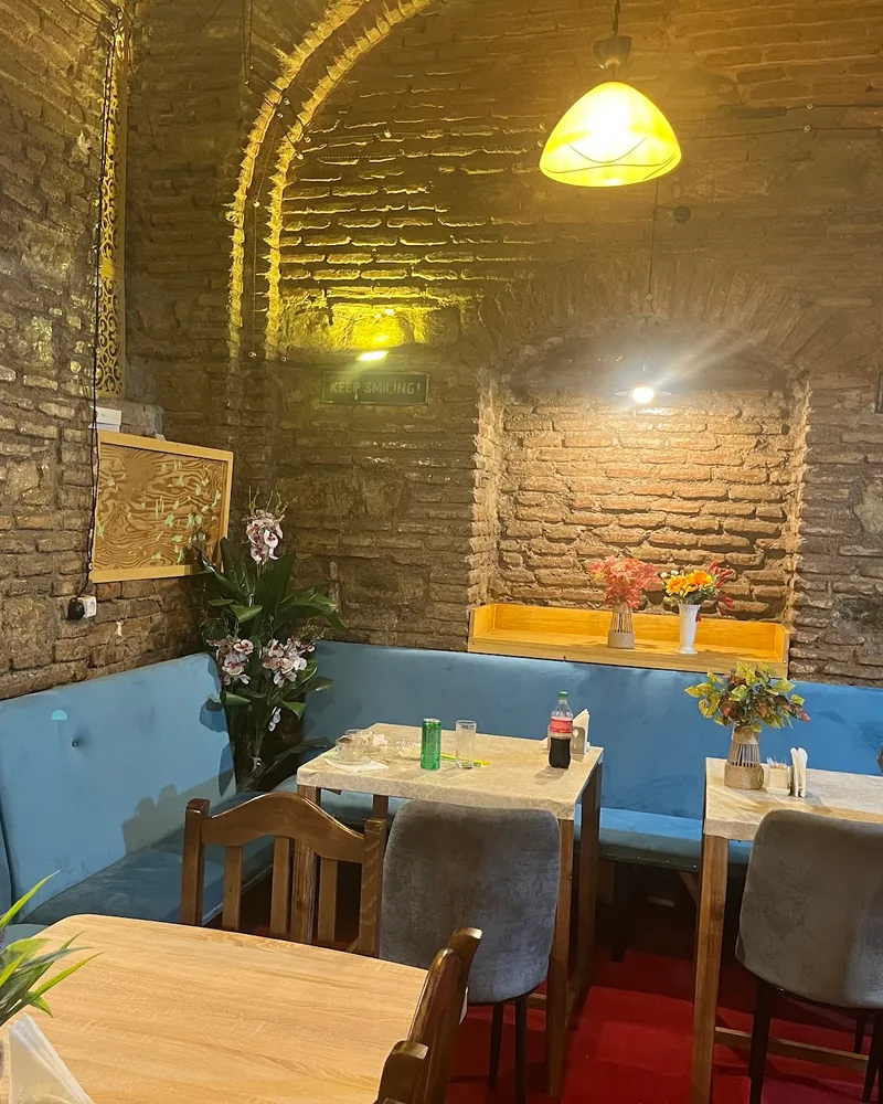 Brick-vaulted dining room with blue banquettes and aquarium at Al Madina Cave