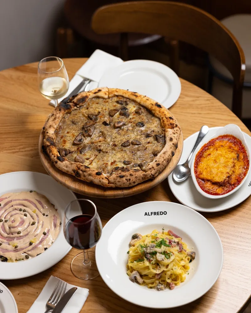 Spread of pizza, pasta, vitello tonnato, and parmigiana with wine at Alfredo