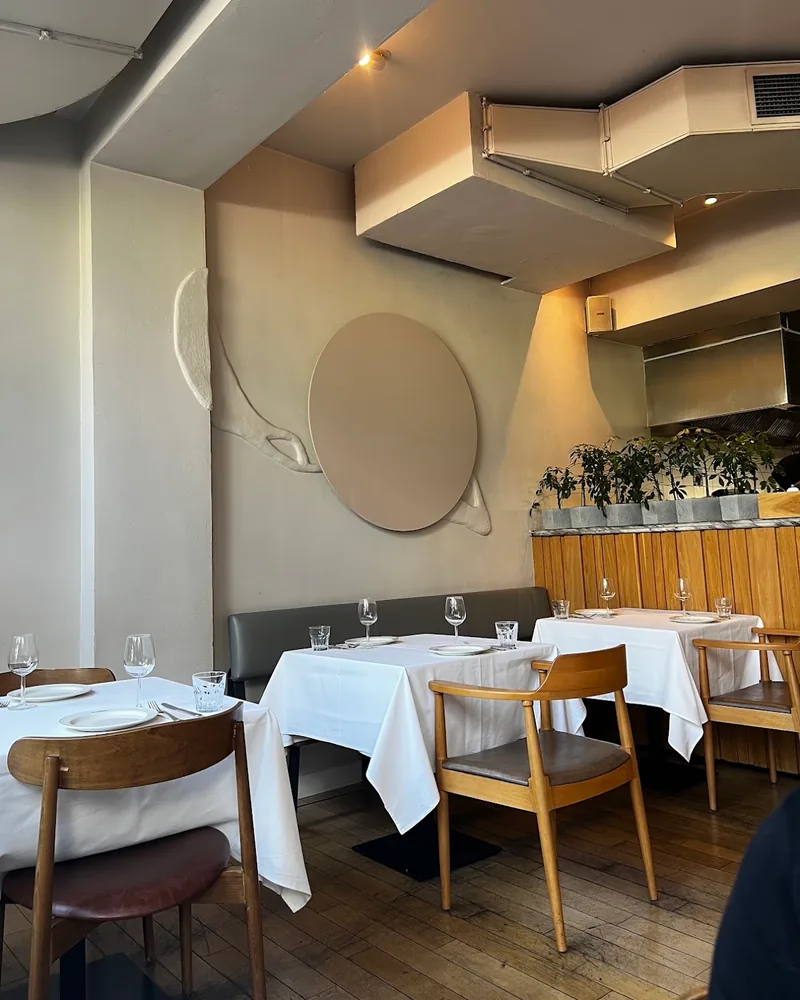 Dining area with white tablecloth tables and minimalist wall decor at Alfredo