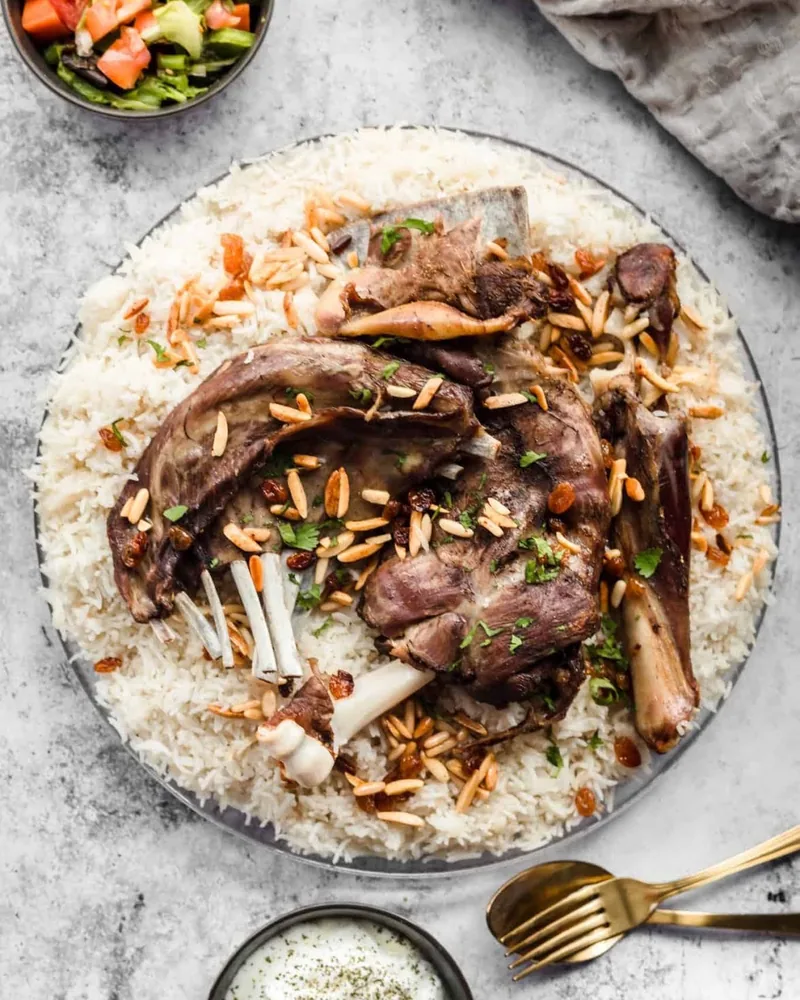 Roast lamb mandi on a large platter of rice with nuts at Aroma