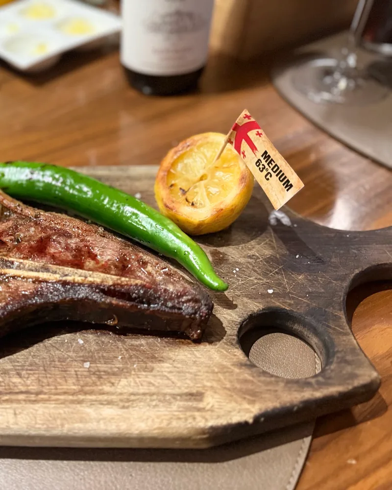 T-bone steak on a wooden board with grilled pepper and lemon at Asado Steakhouse