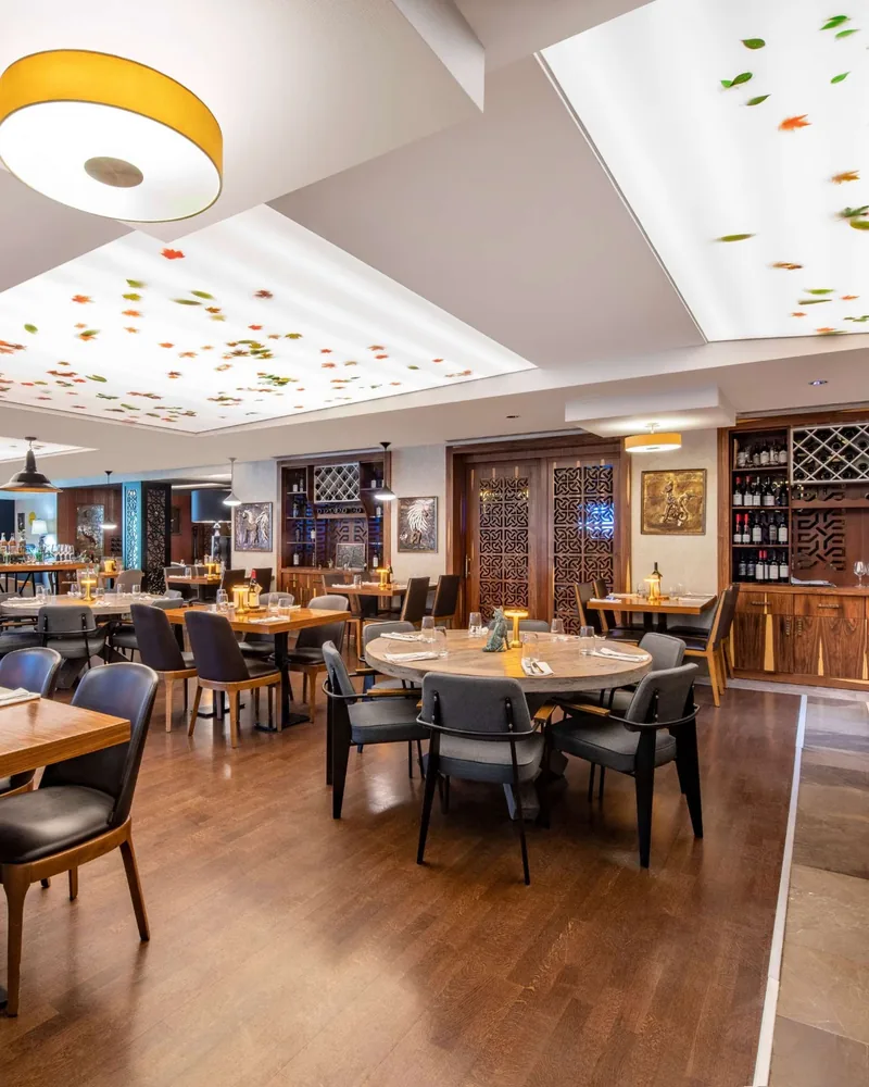 Dining room with wooden tables and illuminated ceiling panels at Asado Steakhouse