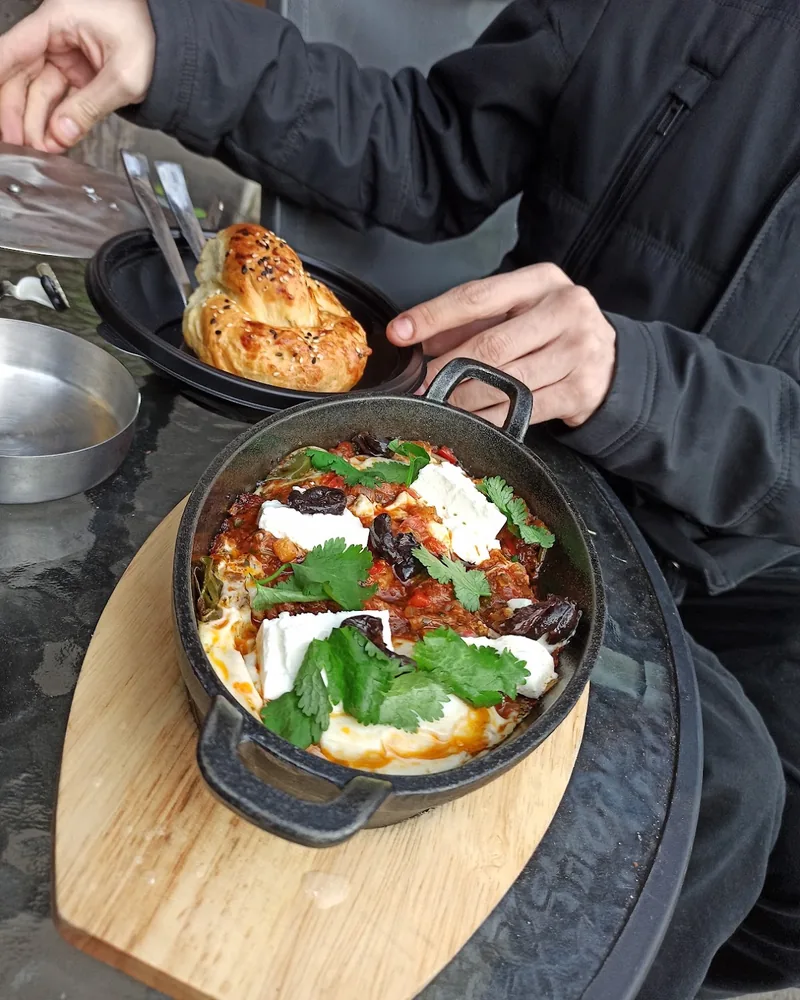 Shakshuka with feta and herbs in an iron skillet with bread at Ashkara Falafel