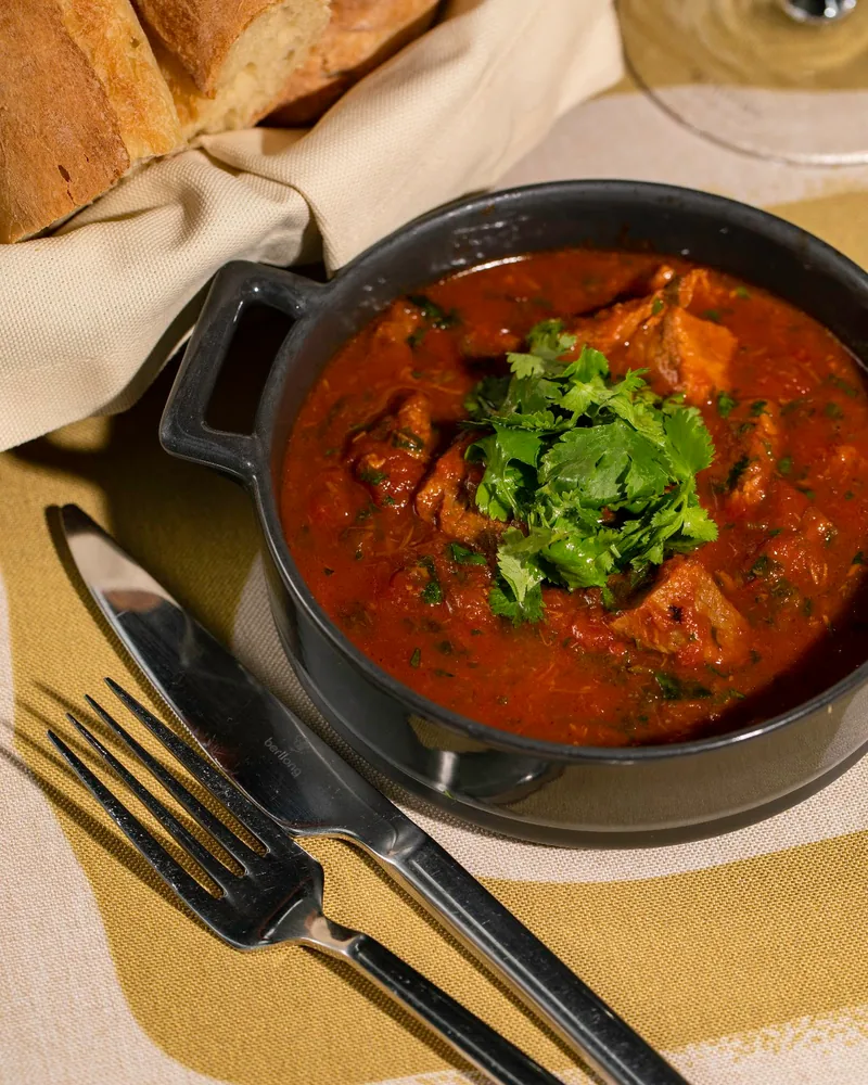 Georgian meat stew with fresh coriander in a black pan at Badagoni