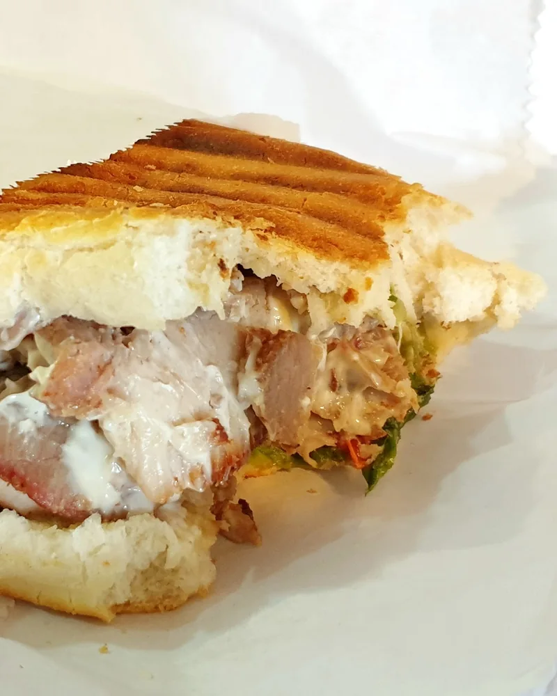 Pressed meat sandwich cut in half in paper wrapping at Balu BBQ shaurma