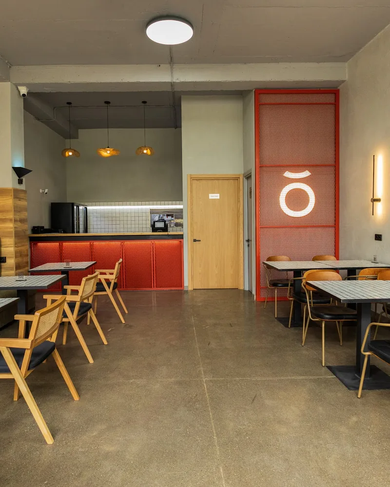 Dining room with wooden chairs and an orange mesh accent wall at Bangkok Digomi