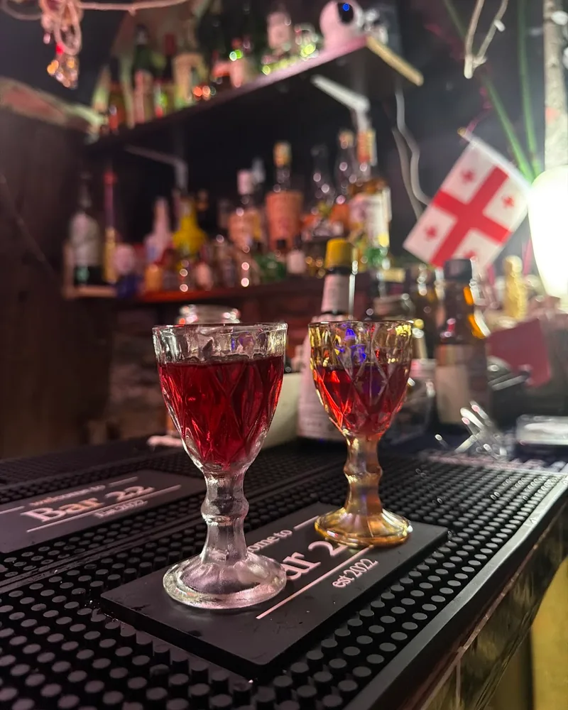 2 red drinks in cut-glass stemmed glasses on the bar at Bar 22, with a Georgian flag behind