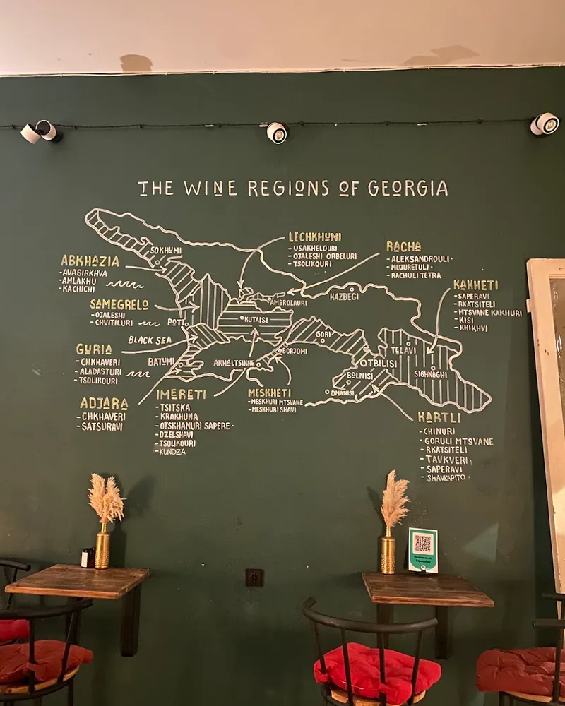 Wine map mural on a green wall with small tables at Bar Happens