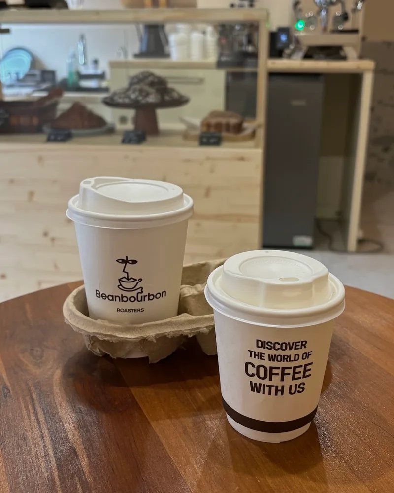 Takeaway coffee cups on a wooden table at Beanbourbon Roasters