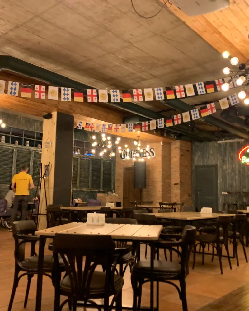 Pub dining hall with wooden tables and flag bunting at Beer Time
