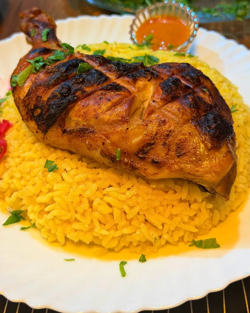 Grilled chicken over yellow rice with dipping sauce at Beirut