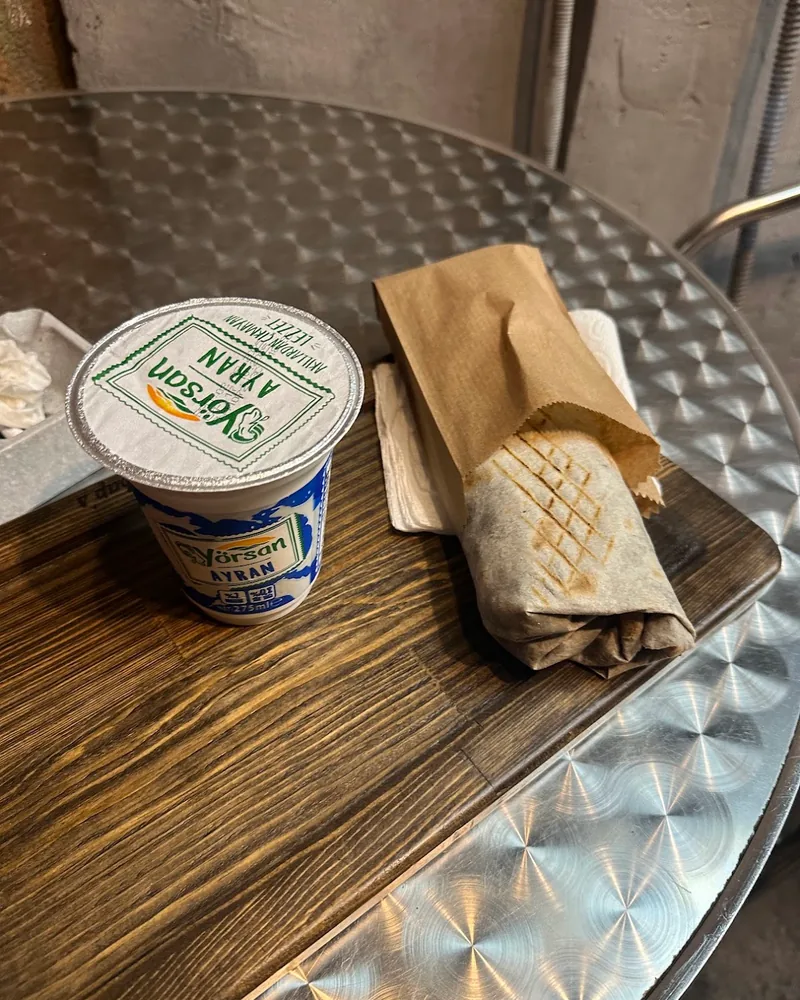 Grilled shawarma wrap in paper with ayran cup at Berlin Shaurma