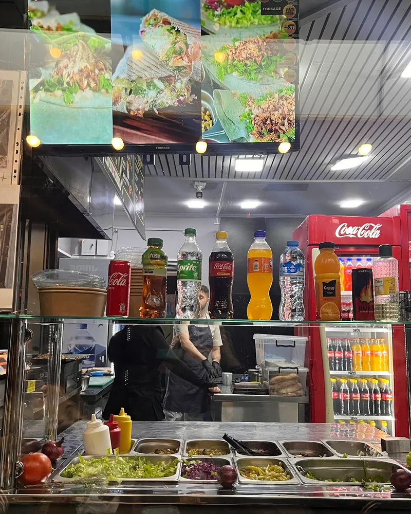 Shawarma counter with condiment station and bottled drinks at Berlin Shaurma