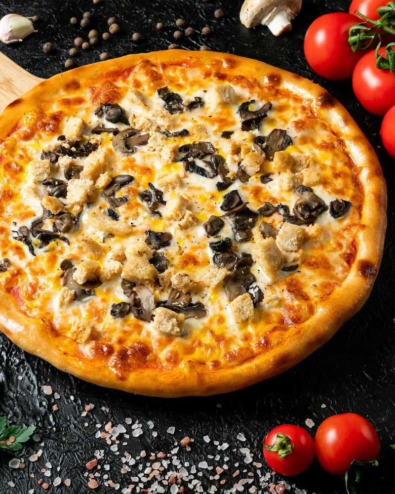 Chicken and mushroom pizza on a wooden peel at Best Pizza in Tbilisi