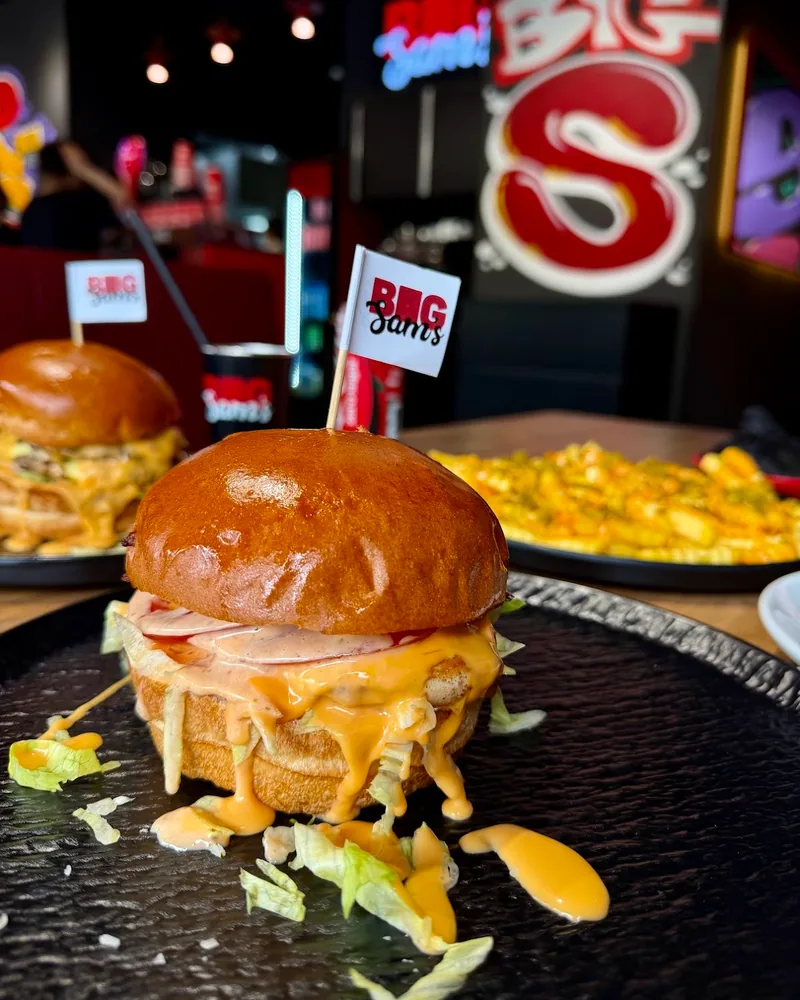 Saucy burger with flag on a black plate at Big Sam's