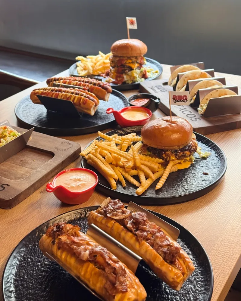 Table spread of burgers, hot dogs, crinkle-cut fries, and tacos at Big Sam's