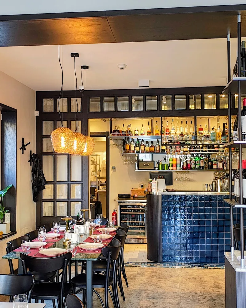 Dining room with wine bottle racks and bar counter in background at Bistro Conili