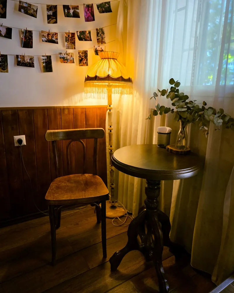 Seating corner with wooden chair, small table and fringe lamp at Black Cup