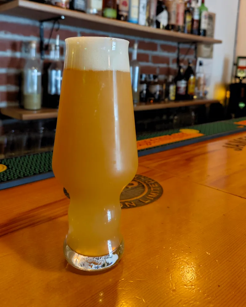 Glass of hazy beer on a wooden bar counter at Black Dog Bar