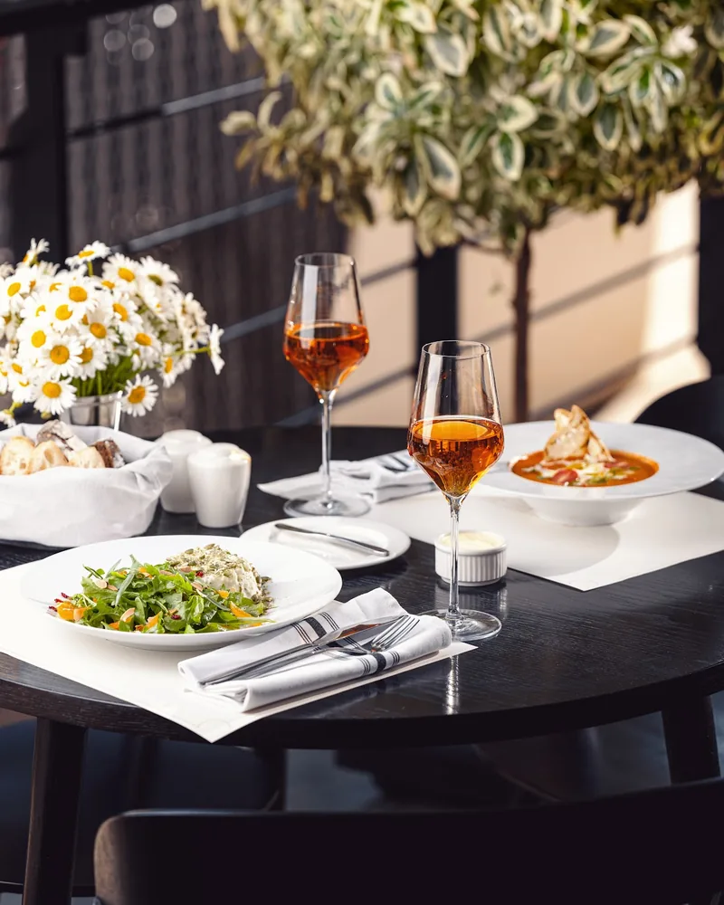 Wine and plated dishes on an outdoor terrace table at Brasserie Buvette
