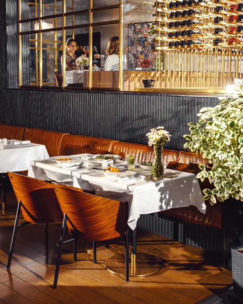 Dining table with leather banquette and wine rack partition at Brasserie Buvette