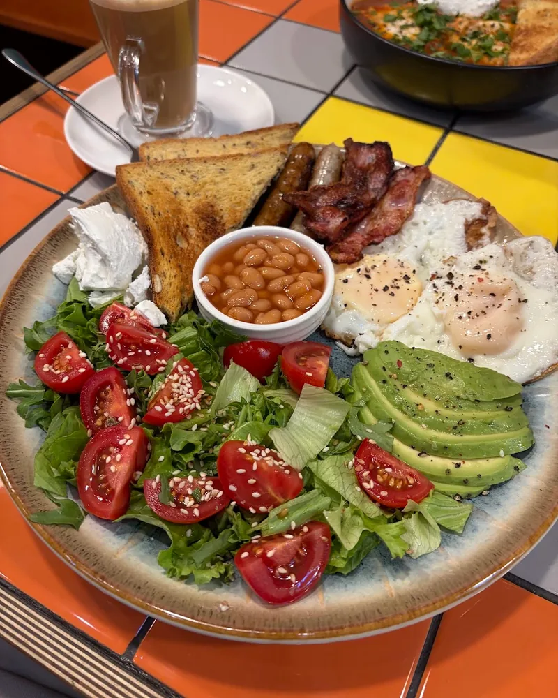 Full breakfast plate with toast, eggs, beans, avocado, and salad at Brunch & Dine