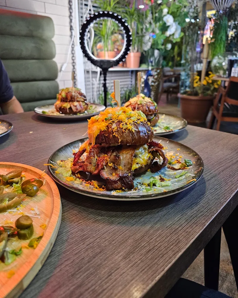 Bacon cheeseburger garnished with grated cheese and toppings at Burger Lions
