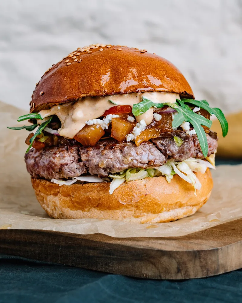 Burger on parchment paper over a wooden board at Burger Space