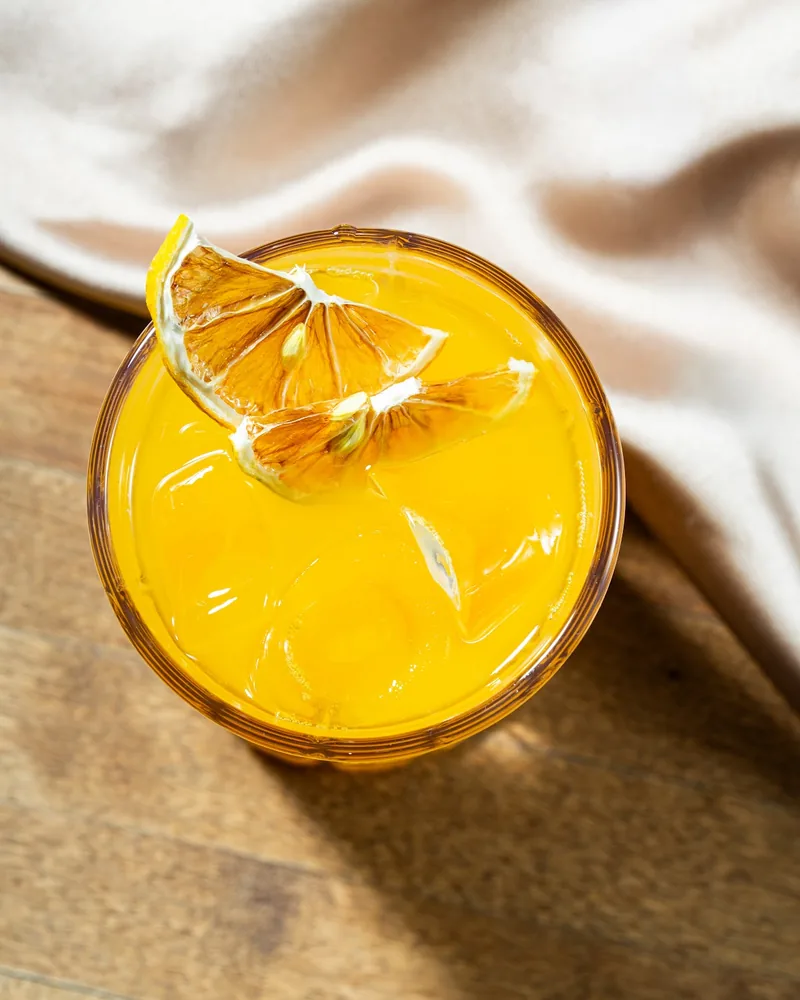 Yellow cocktail garnished with dried citrus slices at Buro Bar