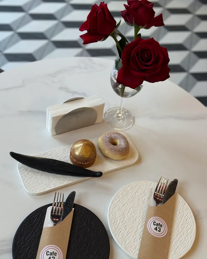Desserts on a textured platter beside red roses at Cafe 43