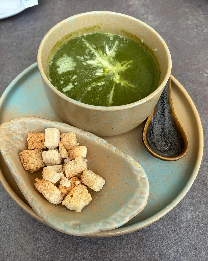 Green soup with croutons on a ceramic platter at Cafe Daphna Meidan