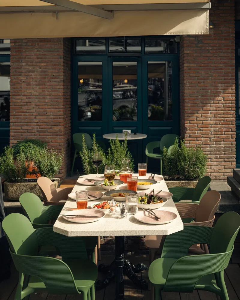 Outdoor patio dining table with green chairs at Cafe Daphna Meidan