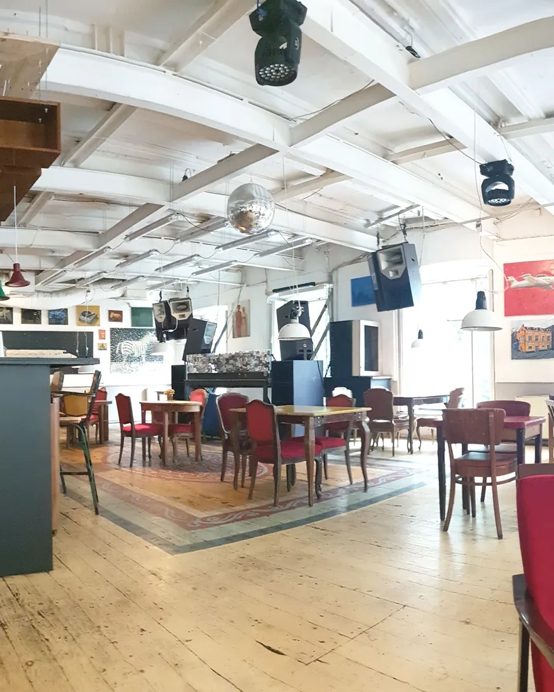 Spacious hall with wooden floors, exposed ceiling beams and vintage seating at Cafe Gallery