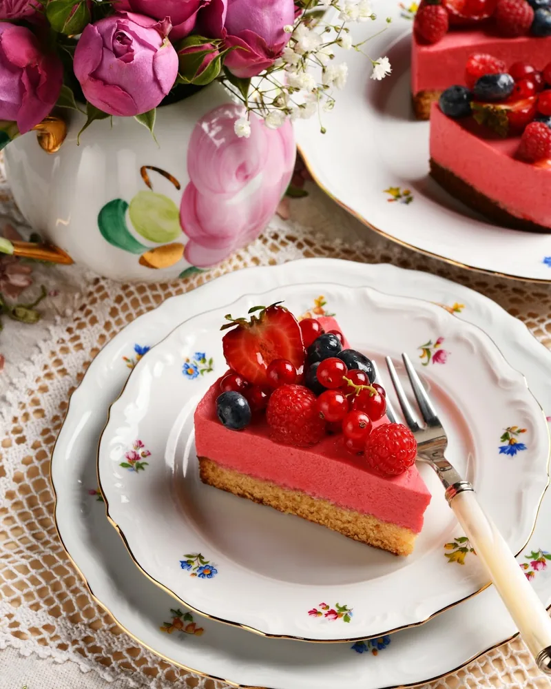 Slice of berry mousse cake on a porcelain plate at Cafe Madeleine