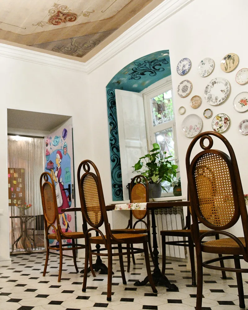 Dining area with painted ceiling and decorative wall plates at Cafe Madeleine