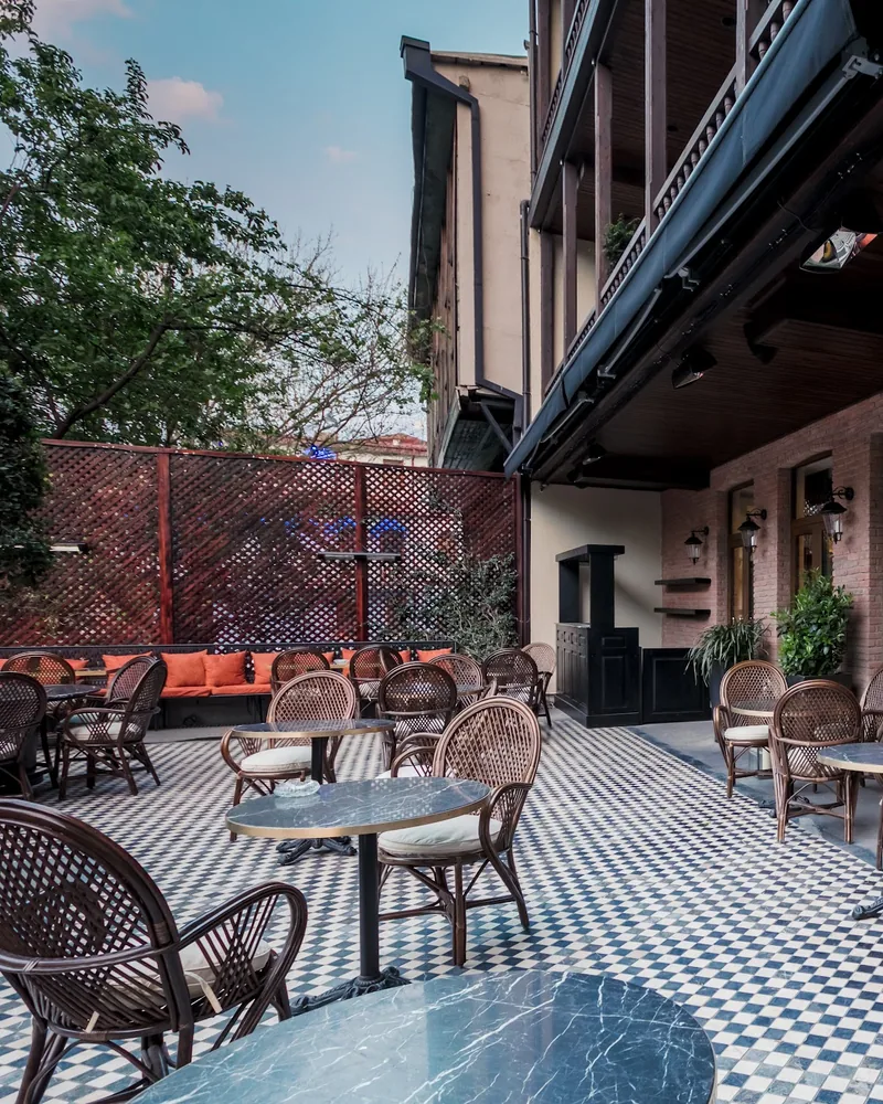 Courtyard patio with checkerboard tile and wicker armchairs at Cafe Museum
