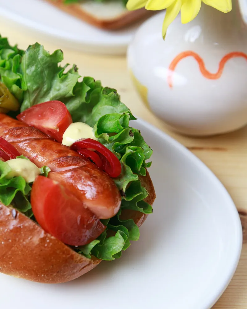Hot dog with lettuce and tomatoes on an oval plate at Cafe Mziuri