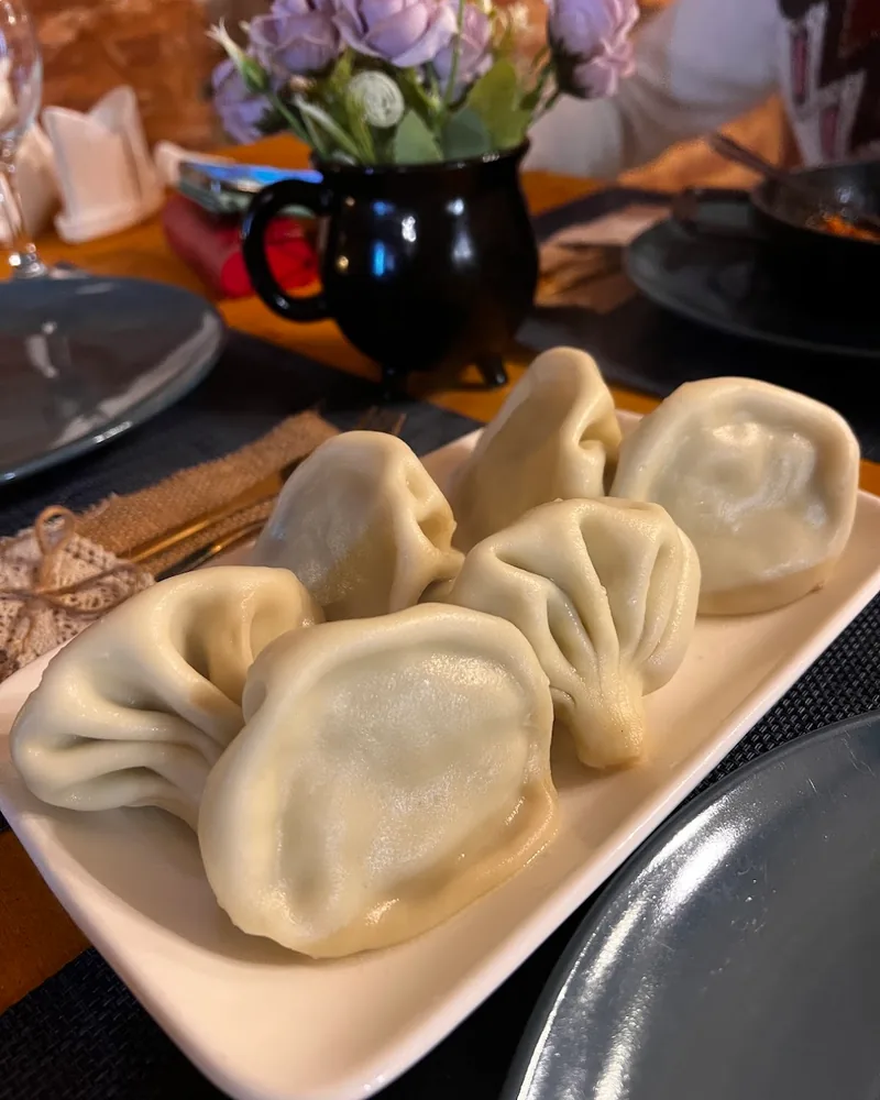 Boiled khinkali with their pleated tops on a white rectangular plate at Cafe Nice