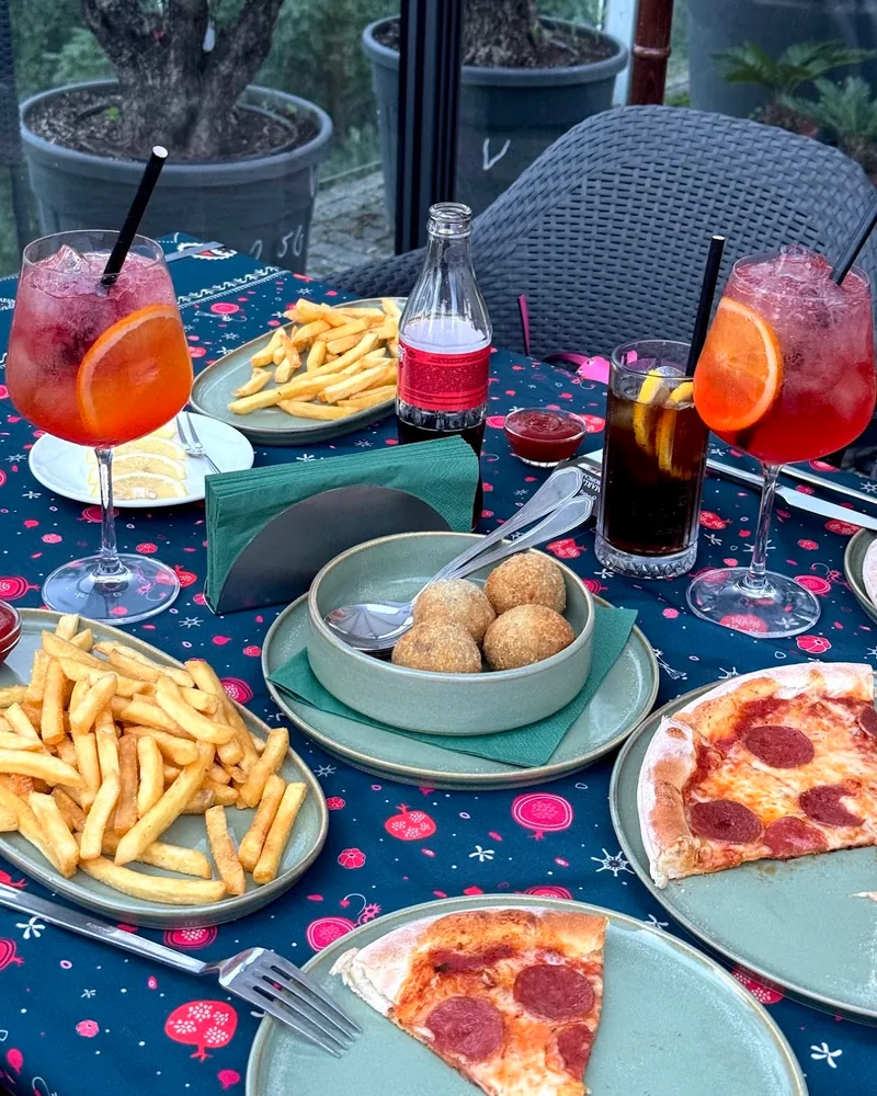 Table spread of spritzes, pizza, fries, and arancini at Cafe Verde