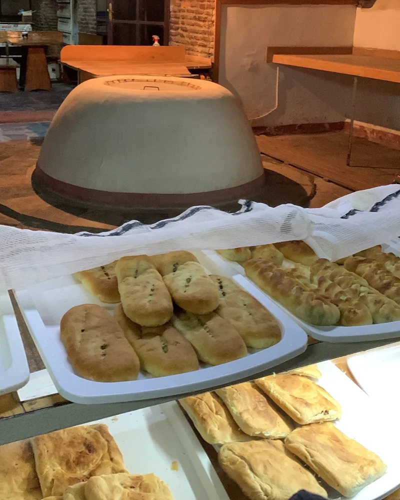 Pastries and bread with a traditional clay oven in the background at Caravanserai Bakery