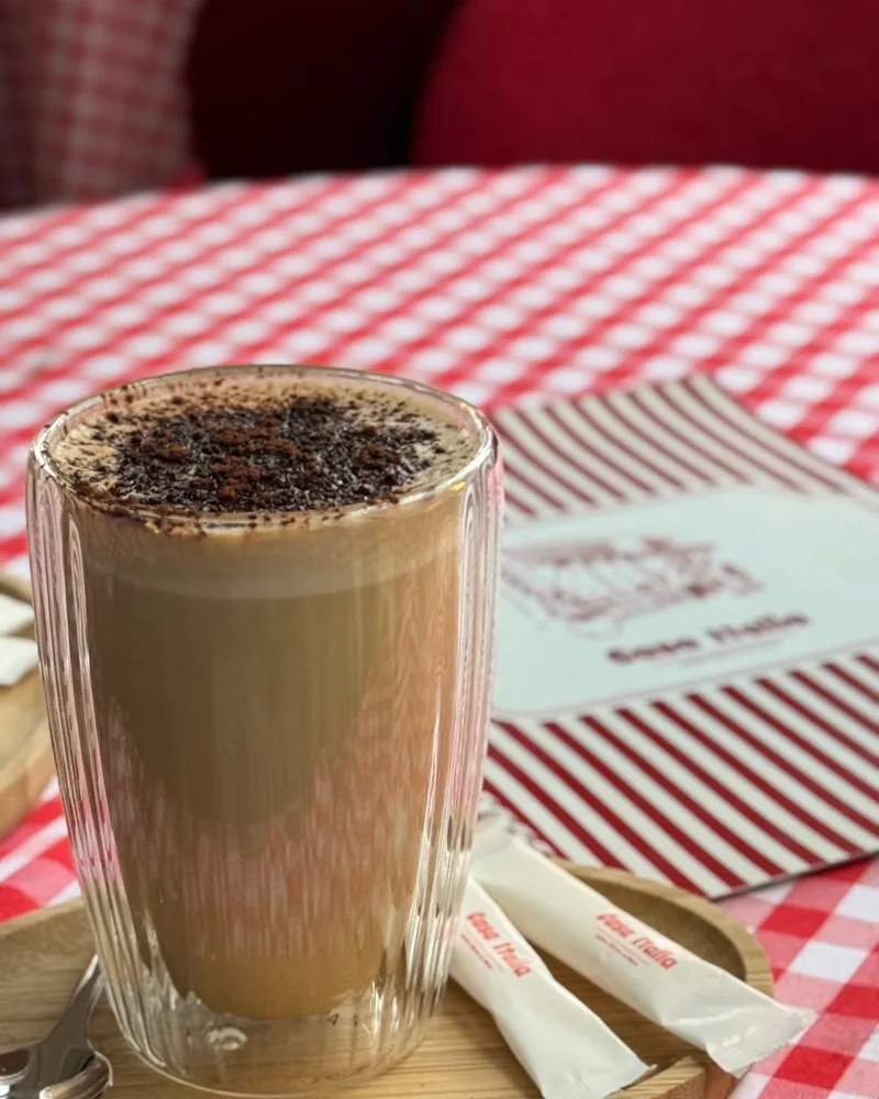 Latte topped with cocoa in a double-walled glass at Casa Italia
