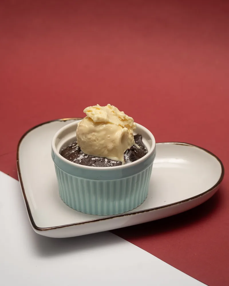 Chocolate souffle with vanilla ice cream in a ramekin on a heart plate at Casa Italia