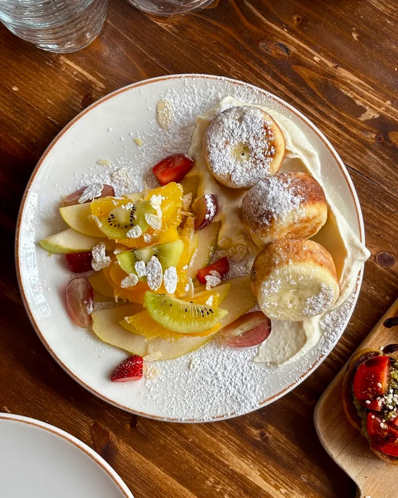 Syrniki with sliced fresh fruit and cream at Chaduna