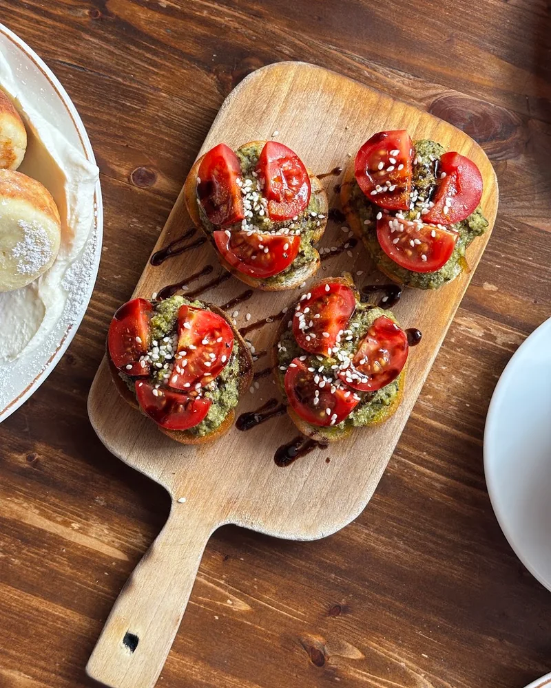 Bruschetta with pesto and tomatoes on a wooden paddle at Chaduna